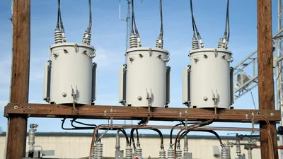 Three-phase wye delta transformer bank installed on a utility pole structure with secondary busbar connections